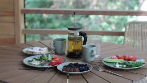 Casual breakfast with berries, veggies, and tea on a wooden porch table.